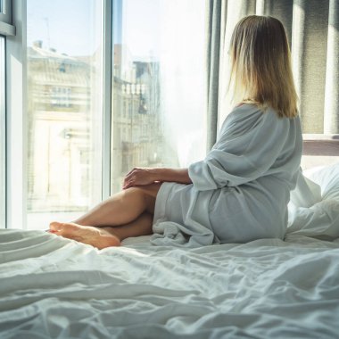 Havluyla yatakta oturup meditasyon yapan genç bir kadın.