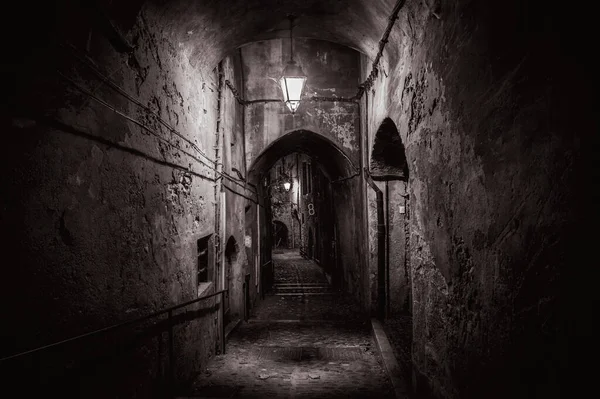 dark street at night in the city crest. Stone walls in a historic town. A lamppost hangs