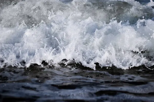 stock image The surface of foamy sea water with a wave, close-up. Shallow depth of field.