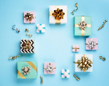 Yılbaşı kartı. Altın ve gümüş madalyalar, pastel mavi kağıt arka planda hediyeler. Noel, kış, yeni yıl konsepti. Düz konum, üst görünüm, kopyalama alanı.