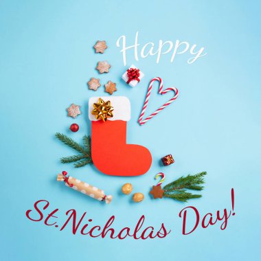 Aziz Nicholas Günü - Kırmızı çizme şekerli, baharatlı zencefilli kurabiye ve mavi arka planda 6 Aralık için hediyeler. Alman, Hollanda, Belçika Noel tüketimi Nikolaus, üst görünüm, kopyalama alanı.