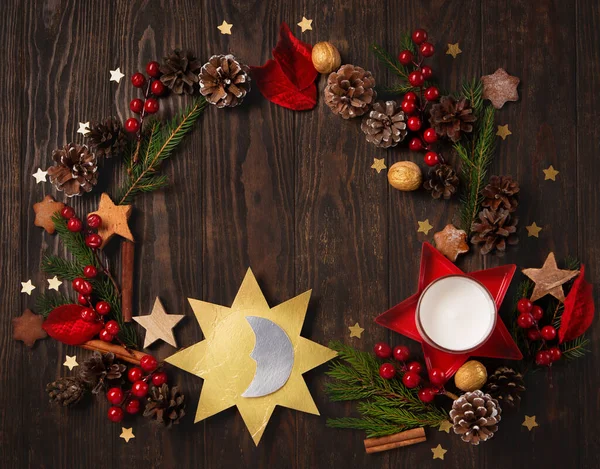 Winter solstice day, December 21. Longest night in the year concept. Sun and moon symbol, Christmas trees, pine cones, paddub branches with red berries, candle on dark wooden background, top view.