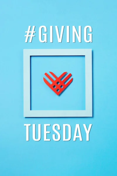 Giving Tuesday, global day of charitable giving after Black Friday shopping day. Charity, give help, donations support concept. Red paper heart and empty blue frame on blue background. Top view, copy space, flat lay.