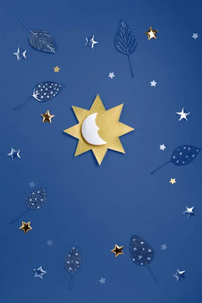 Winter solstice day holiday, December 21. Longest night in the year concept. Sun, moon, golden stars and Winter forest symbol on blue  background. Flat lay, top view, copy space