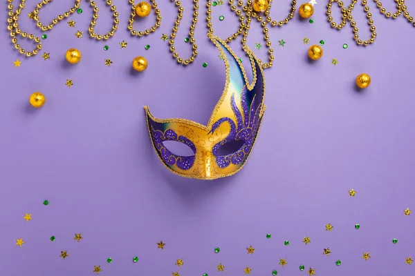 Mardi Gras King Cake masquerade festival carnival mask, gold beads and golden, green confetti on purple background. Holiday party invitation, greeting card concept.