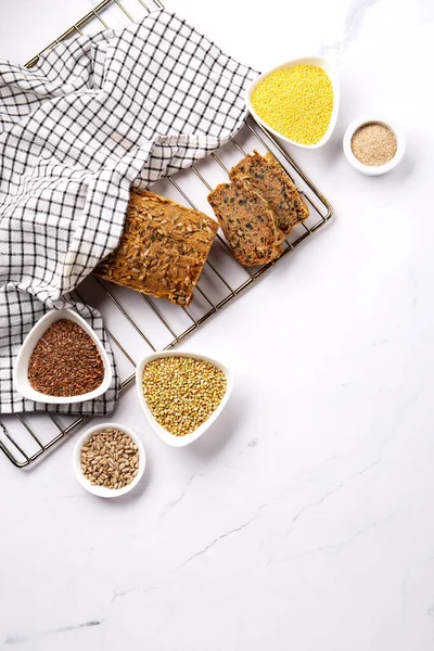 Gluten Free Homemade Bread. Healthy eating, dieting, balanced food concept. Cereals gluten-free (millet, buckwheat), psyllium husks, flax seeds, sunflower seeds on gray marble background.