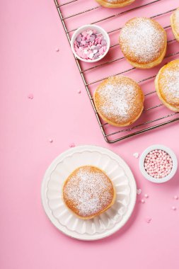 Happy National donut day or Valentines Day Concept. Donuts doughnuts with icing sugar and sugar sprinkles on pink background, copy space. Colorful carnival or birthday party card.