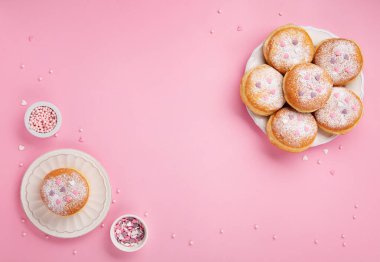 Happy National donut day or Valentines Day Concept. Donuts doughnuts with icing sugar and sugar sprinkles on pink background, copy space. Colorful carnival or birthday party card.