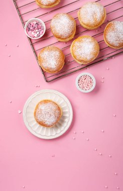 Happy National donut day or Valentines Day Concept. Donuts doughnuts with icing sugar and sugar sprinkles on pink background, copy space. Colorful carnival or birthday party card.