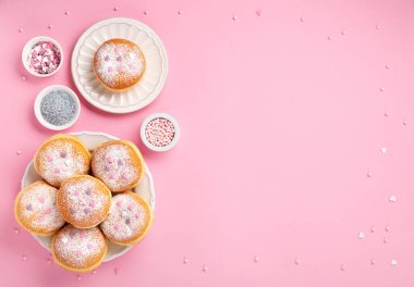 Happy National donut day or Valentines Day Concept. Donuts doughnuts with icing sugar and sugar sprinkles on pink background, copy space. Colorful carnival or birthday party card.