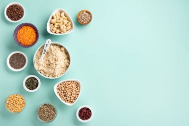 Plant based protein food (legumes, lentils, beans, seeds) and Healthy dry Pea Protein Powder, food supplement, Fitness nutrition on blue green background. Vegan, vegetarian food concept.
