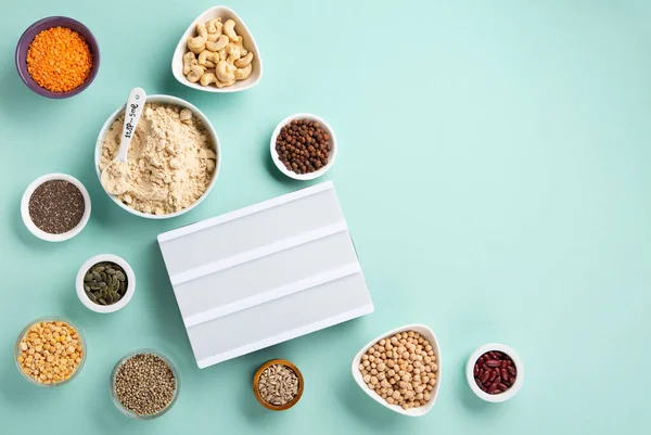 Plant based protein food (legumes, lentils, beans, seeds) and Healthy dry Pea Protein Powder, food supplement, Fitness nutrition on blue green background. Vegan, vegetarian food concept.