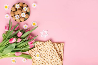 Yahudi bayramı tebrik kartı konsepti. Üzerinde matza, fındık, lale ve papatya çiçekleri var. Seder Pesach bahar tatili arka planı, üst görünüm, kopyalama alanı.