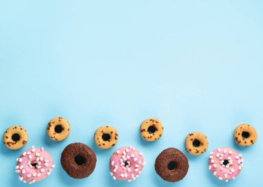 Donuts doughnuts with chocolate, marshmallow and sugar sprinkles on blue background, copy space. Colorful carnival or birthday party card. Happy National donut day Concept. 