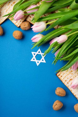 Yahudi bayramı tebrik kartı konsepti. Matza, fındık, lale çiçeği mavi masada. Seder Pesach bahar tatili arkaplanı, üst manzara, kopyalama alanı..