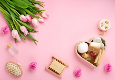 Natural eco friendly beauty skin care products, spa accessories for women and spring tulip flowers on pink background. Zero waste self care heart shape gift box for mothers day, womans day, birthday.