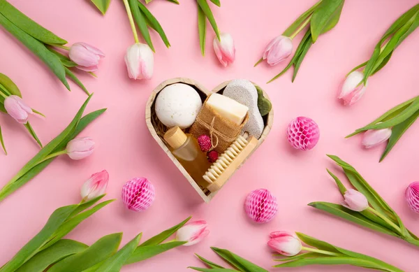 Natural eco friendly beauty skin care products, spa accessories for women and spring tulip flowers on pink background. Zero waste self care heart shape gift box for mothers day, womans day, birthday.