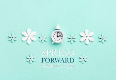White alarm clock and Daisy Flowers on blue mint background. Spring forward, Time Change, Daylight Saving Time Ends, Changing the time on the watch to spring time, Summer back concept.