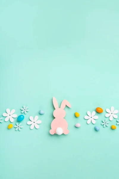 Pink Easter Bunny, Sweet Colorful Easter Eggs, daisy flowers on pastel blue background. Happy Easter greeting card concept, copy space.