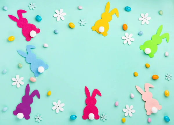 Colorful Easter Bunnies, Sweet Colorful Easter Eggs, daisy flowers on pastel blue mint background. Happy Easter greeting card concept, copy space.