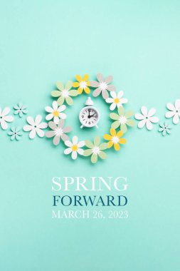 White alarm clock and Daisy Flowers on blue mint background. Spring forward, Time Change, Daylight Saving Time Ends, Changing the time on the watch to spring time, Summer back concept.