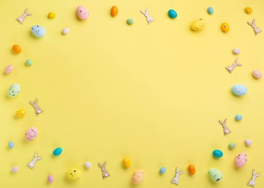Renkli Paskalya yumurtaları ve pastel sarı arka planda bahar beyaz papatya çiçekleri. Paskalya tebrik kartı konseptin kutlu olsun. Düz konum, üst görünüm, kopyalama alanı.