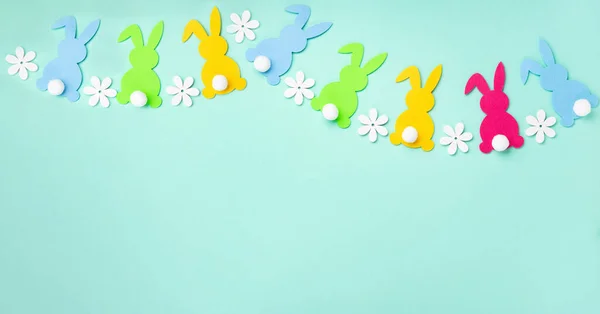 Colorful Easter Bunnies, Sweet Colorful Easter Eggs, daisy flowers on pastel blue mint background. Happy Easter greeting card concept, copy space.