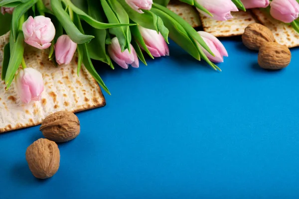 ユダヤ人の休日マツア ナッツ 青いテーブルのチューリップの花と過越の挨拶カードの概念 Seder Pesach春休みの背景 トップビュー コピースペース — ストック写真