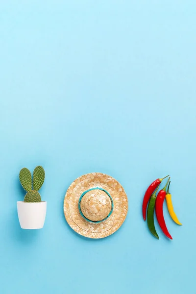 Mexican background fiesta with Traditional Mexican chilli pepper, cactus and sombrero hat on blue background. Cinco de Mayo (Fifth of May) celebration concept. Top view, copy space.