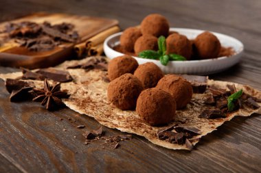 Ev yapımı vegan çikolatalı trüf, yuvarlak çikolatalı, kakao tozlu. Kaba ahşap arka planda koyu çikolata ve hindistan cevizi ezmesi. El yapımı, glütensiz, sağlıklı tatlı konsepti..