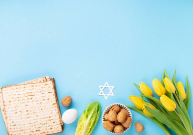 Yahudi bayramı tebrik kartı konsepti matza matzoh (Yahudi bayramı ekmeği), ceviz, mavi masada sarı lale çiçekleri. Seder Pesach bahar tatili arka planı, üst görünüm.