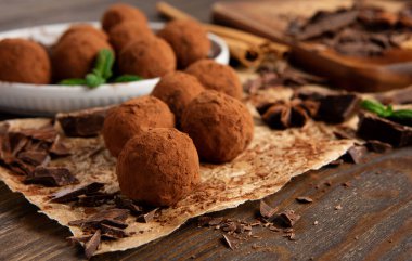Ev yapımı vegan çikolatalı trüf, yuvarlak çikolatalı, kakao tozlu. Kaba ahşap arka planda koyu çikolata ve hindistan cevizi ezmesi. El yapımı, glütensiz, sağlıklı tatlı konsepti..
