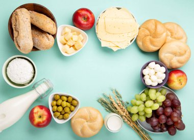 Mutlu Shavuot şenlik kartları. Yahudi dini bayramı konsepti. Süt ürünleri, meyveler, peynir, ekmek, süt şişesi, süzme peynir, naneli buğday. Üst görünüm, alanı kopyala.
