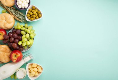 Mutlu Shavuot şenlik kartları. Yahudi dini bayramı konsepti. Süt ürünleri, meyveler, peynir, ekmek, süt şişesi, süzme peynir, naneli buğday. Üst görünüm, alanı kopyala.