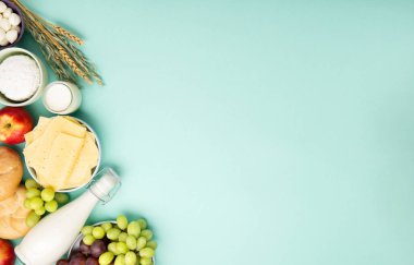 Mutlu Shavuot şenlik kartları. Yahudi dini bayramı konsepti. Süt ürünleri, meyveler, peynir, ekmek, süt şişesi, süzme peynir, naneli buğday. Üst görünüm, alanı kopyala.