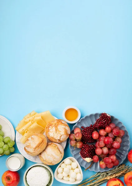 stock image Happy Shavuot festive card. Jewish religious holiday concept. Dairy products, grapes, cheese, bread, milk, cottage cheese, wheat, honey on blue background. Top view, copy space.