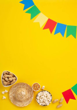 Brezilya Karnavalı Festa Junina Yaz Festivali konsepti. Brezilya hasır şapkası, patlamış mısır, fıstık ve sarı arka planda renkli bayraklar, üst manzara. Tebrik Kartı, Davetiye veya Tatil Posteri Tasarımı