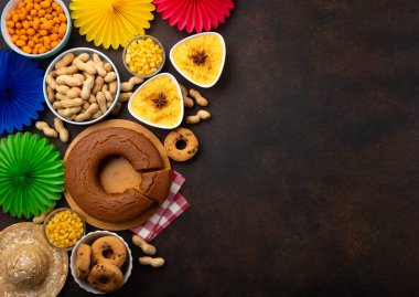Junina Yaz Festivali Karnavalı konsepti. Brezilya hasır şapkası, Mısır keki, fıstık ve ahşap arka planda renkli bayraklar, üst manzara. Tebrik Kartı, Davetiye veya Tatil Posteri Tasarımı