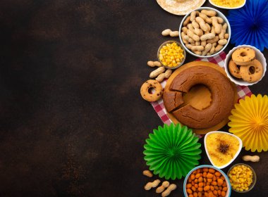 Junina Yaz Festivali Karnavalı konsepti. Brezilya hasır şapkası, Mısır keki, fıstık ve ahşap arka planda renkli bayraklar, üst manzara. Tebrik Kartı, Davetiye veya Tatil Posteri Tasarımı