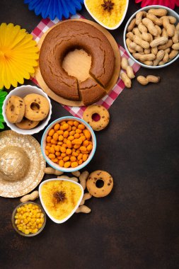 Junina Yaz Festivali Karnavalı konsepti. Brezilya hasır şapkası, Mısır keki, fıstık ve ahşap arka planda renkli bayraklar, üst manzara. Tebrik Kartı, Davetiye veya Tatil Posteri Tasarımı