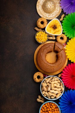 Junina Yaz Festivali Karnavalı konsepti. Brezilya hasır şapkası, Mısır keki, fıstık ve ahşap arka planda renkli bayraklar, üst manzara. Tebrik Kartı, Davetiye veya Tatil Posteri Tasarımı