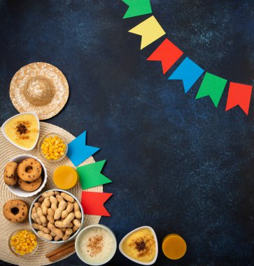 Junina Yaz Festivali Karnavalı konsepti. Brezilya hasır şapkası, Mısır keki, yer fıstığı ve ahşap mavi arka planda renkli bayraklar, üst manzara. Tebrik Kartı, Davetiye veya Tatil Posteri Tasarımı