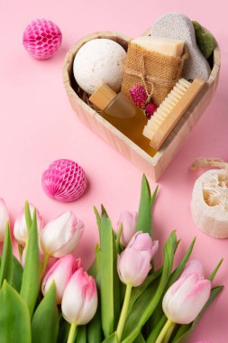 Natural eco friendly beauty skin care products, spa accessories for women and spring tulip flowers on pink background. Zero waste self care heart shape gift box for mothers day, womans day, birthday.