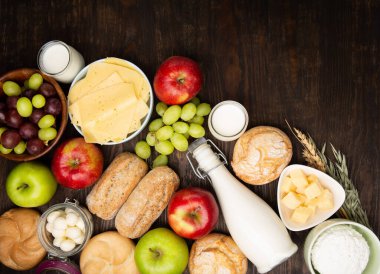 Mutlu Shavuot şenlik kartları. Yahudi dini bayramı konsepti. Süt ürünleri, meyveler, peynir, ekmek, süt şişesi, süzme peynir, koyu ahşap arka planda buğday. Üst görünüm, alanı kopyala.