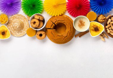 Junina Yaz Festivali Karnavalı konsepti. Brezilya hasır şapkası, Mısır keki, fıstık ve beyaz ahşap arka planda renkli bayraklar, üst manzara. Tebrik Kartı, Davetiye veya Tatil Posteri Tasarımı