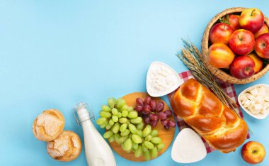 Mutlu Shavuot şenlik kartları. Yahudi dini bayramı konsepti. Süt ürünleri, taze elma, üzüm, peynir, ekmek, süt, süzme peynir, buğday ve bal. Üst görünüm, alanı kopyala.