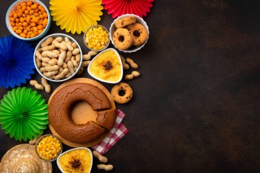 Junina Yaz Festivali Karnavalı konsepti. Brezilya hasır şapkası, Mısır keki, fıstık ve ahşap arka planda renkli bayraklar, üst manzara. Tebrik Kartı, Davetiye veya Tatil Posteri Tasarımı
