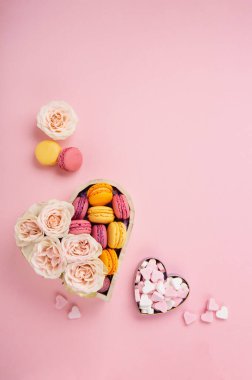 Şenlikli hediye kutusunda kurabiyeler, gül çiçekleri ve pembe arka planda şekerler. Anneler Günü için bayram, kadınlar için sevgililer günü, doğum günü konsepti. Düz konum, mesaj veya metin için boş boşluk