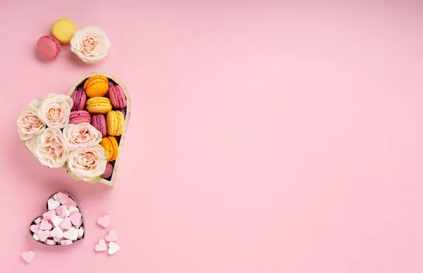 お祝いのギフトボックスで甘いクッキーマカロン ピンクの背景にバラの花やキャンディー 母の日 女性の日のバレンタインデー 誕生日のための概念を提示します トップビュー コピースペース — ストック写真