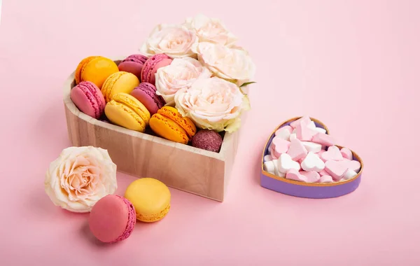 お祝いのギフトボックスで甘いクッキーマカロン ピンクの背景にバラの花やキャンディー 母の日 女性の日のバレンタインデー 誕生日 テキストやメッセージのための空のスペースのための休日の概念を提示します — ストック写真